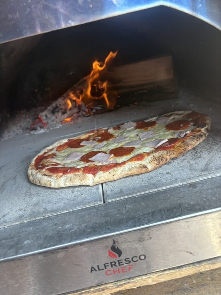 Wood-fired Neapolitan pizza cooking in our 500°C oven at a Cotswolds event