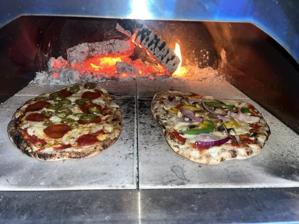 Two Neapolitan pizzas cooking simultaneously in our wood-fired oven
