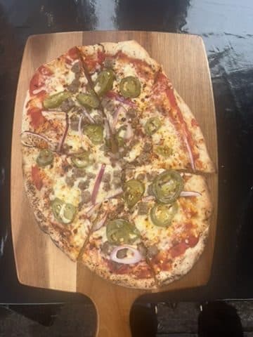 Handcrafted jalapeño pizza on a wooden board at a South West event