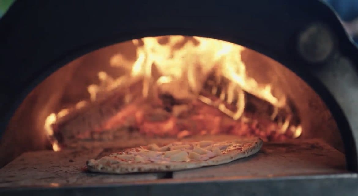Pizza cooking with roaring flames in our professional wood-fired oven